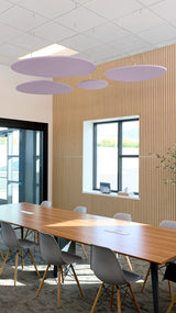 Four purple oval acoustic baffles suspended from ceiling in modern office conference room.