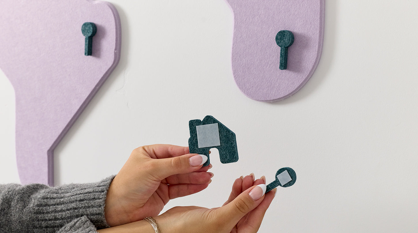 Person holding small green felt piece with a white background