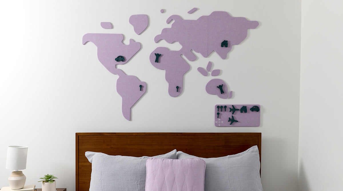 World map wall decoration on a white wall above a bed with purple and gray bedding.