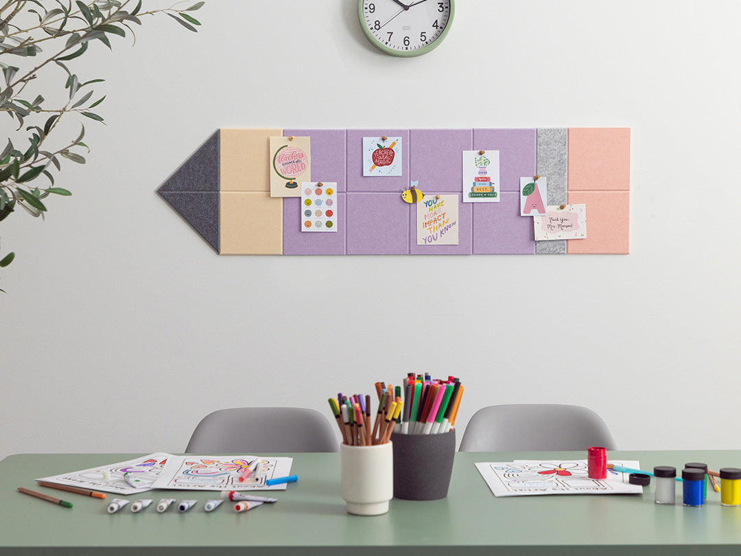 Children's art supplies on a table with a colorful magnetic board on the wall.