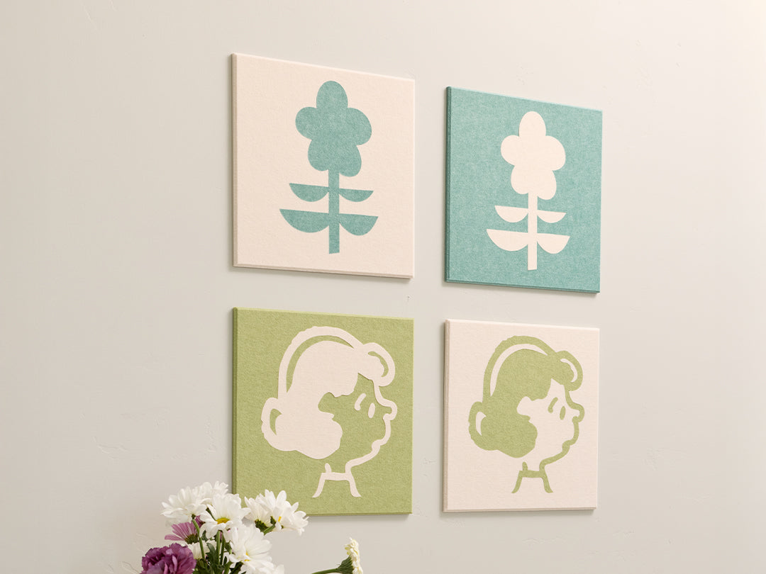 Four square wall art pieces with floral and abstract designs on a white wall.