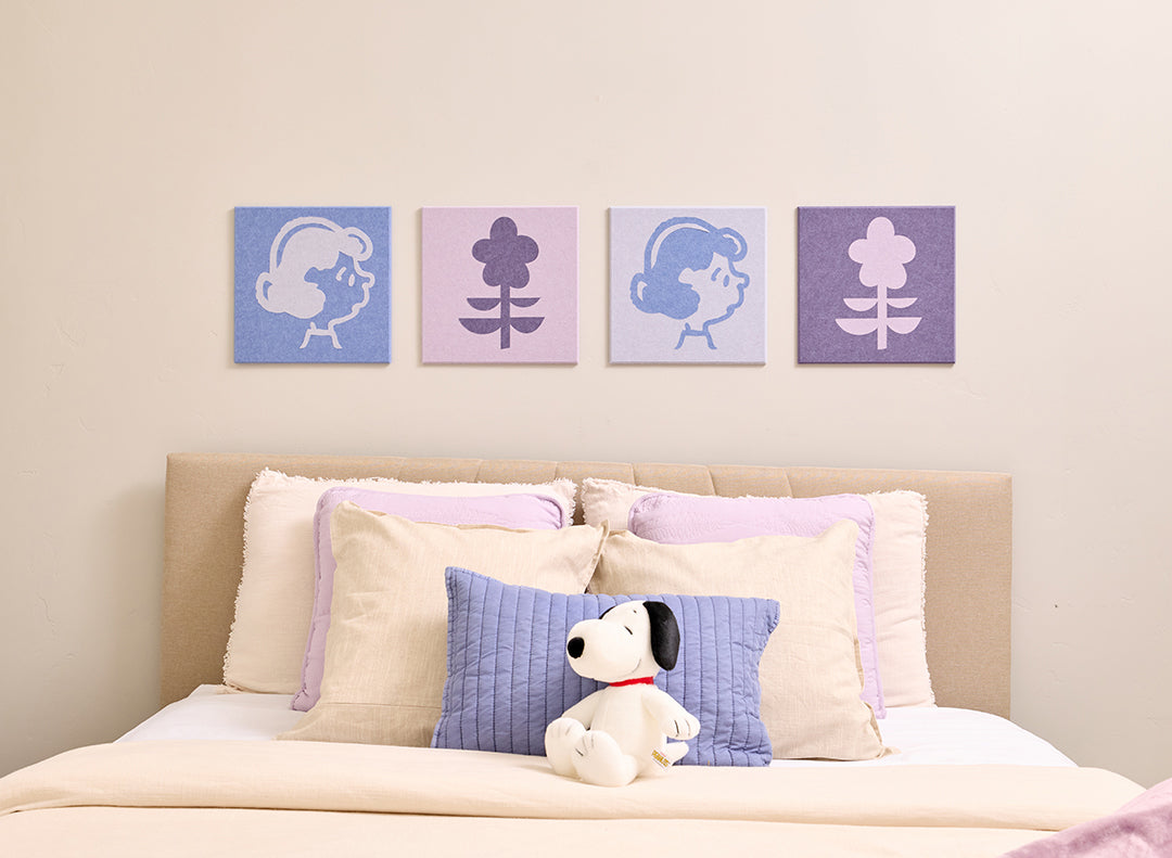 Bedroom with Peanuts Lucy wall art above a bed with a plush toy.