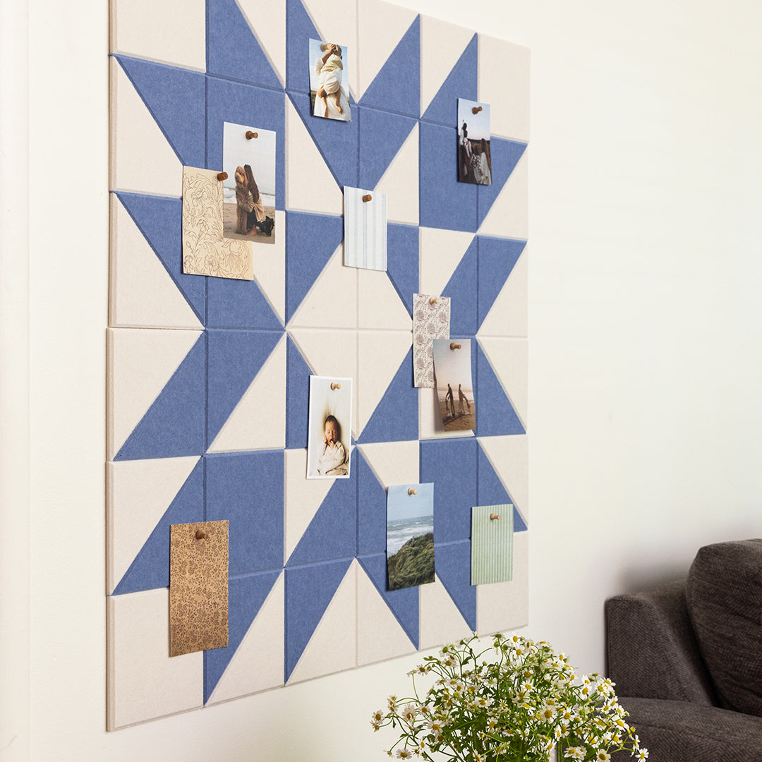 Geometric patterned wall art with pinned photos and a plant in the foreground