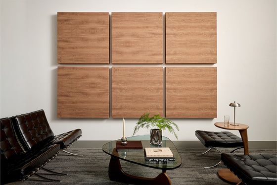 Lobby area with black Barcelona chairs and wood grain acoustic wall panels on a white wall.