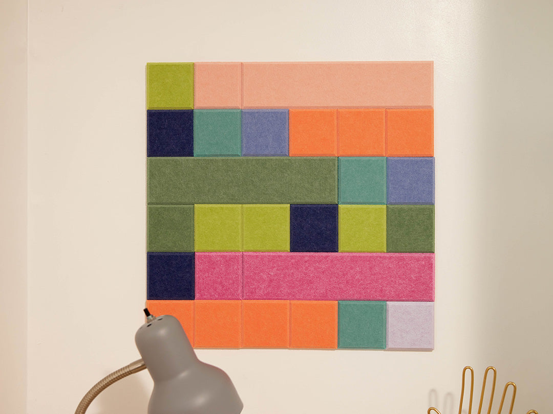 Colorful square wall art on a beige wall with a lamp and decorative item.