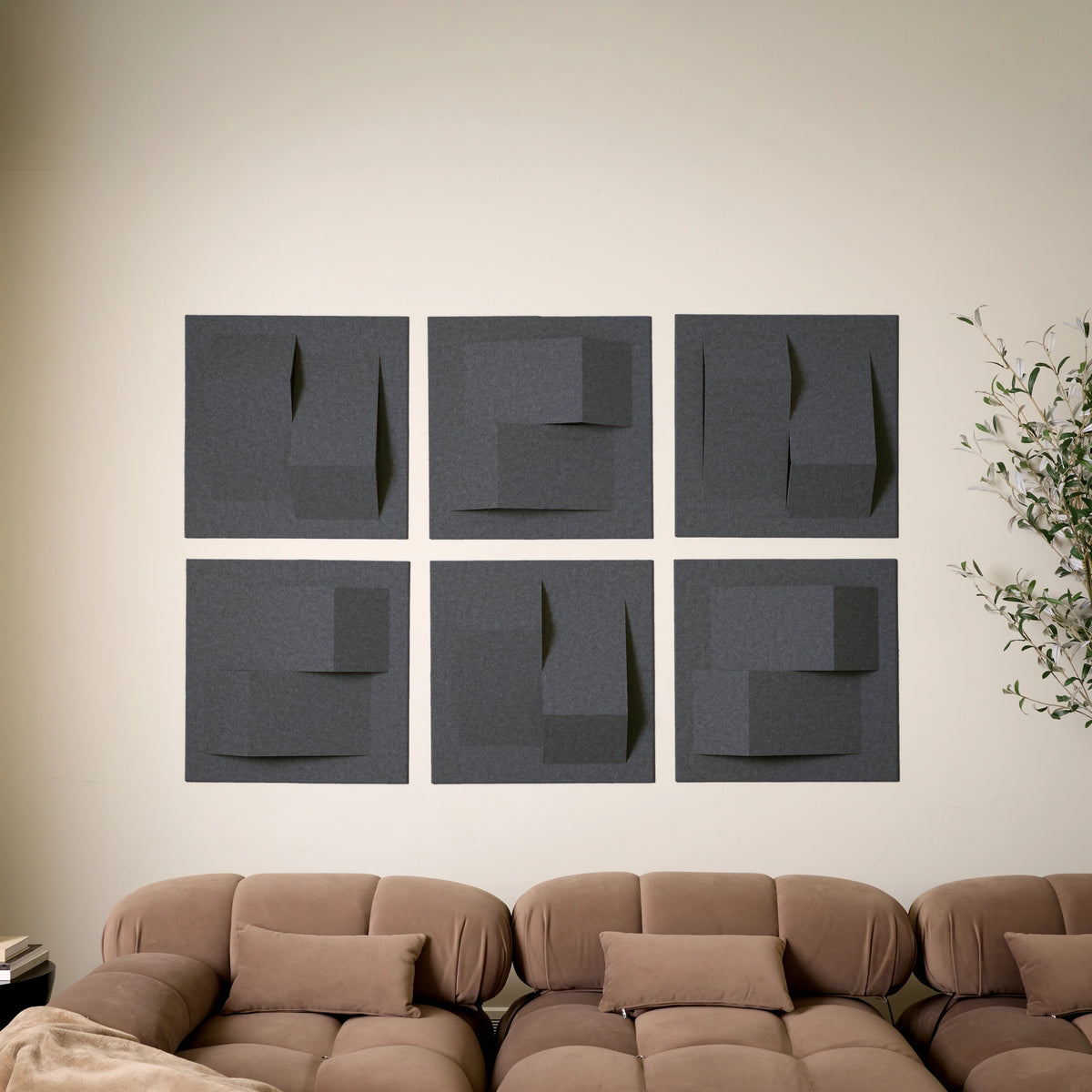 Dark grey acoustic wall tiles with raised geometric shapes used as modern living room decor 