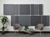 Set of gray fabric acoustic wall panels in varying sizes arranged in two rows on white wall.