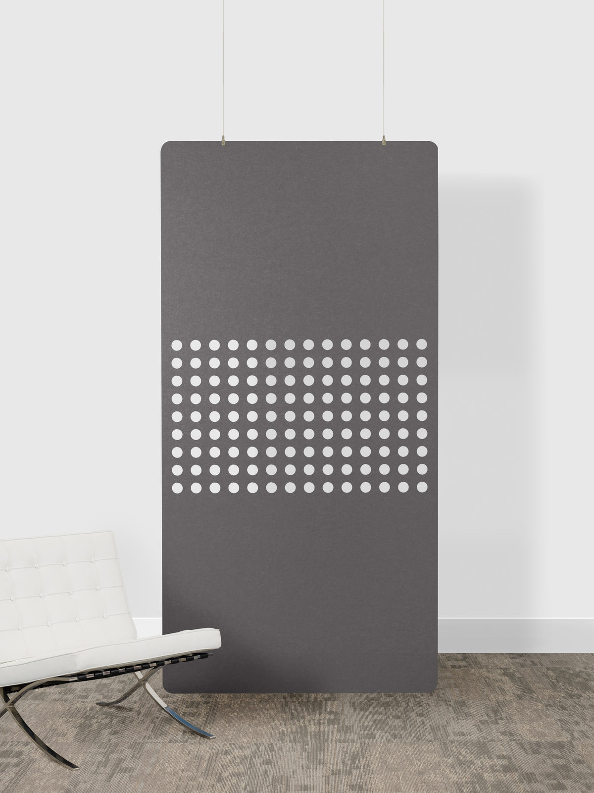 Modern gray radiator with perforated design against a white wall