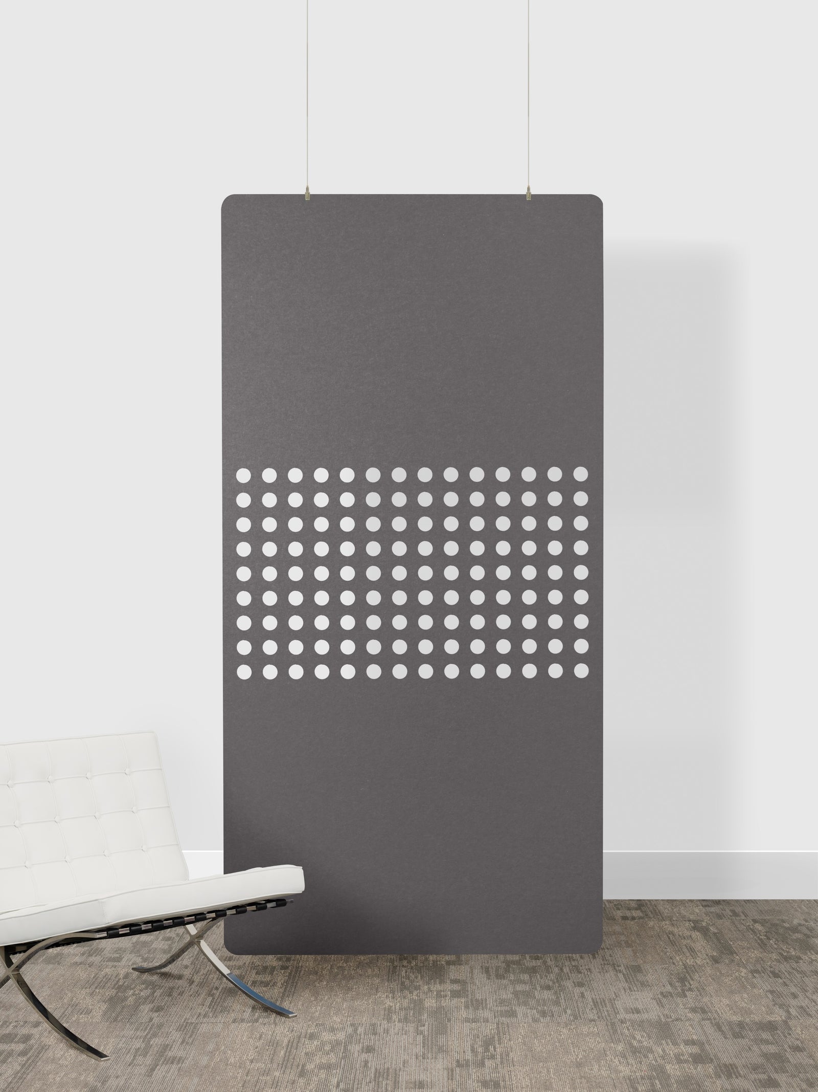 Modern gray radiator with perforated design against a white wall