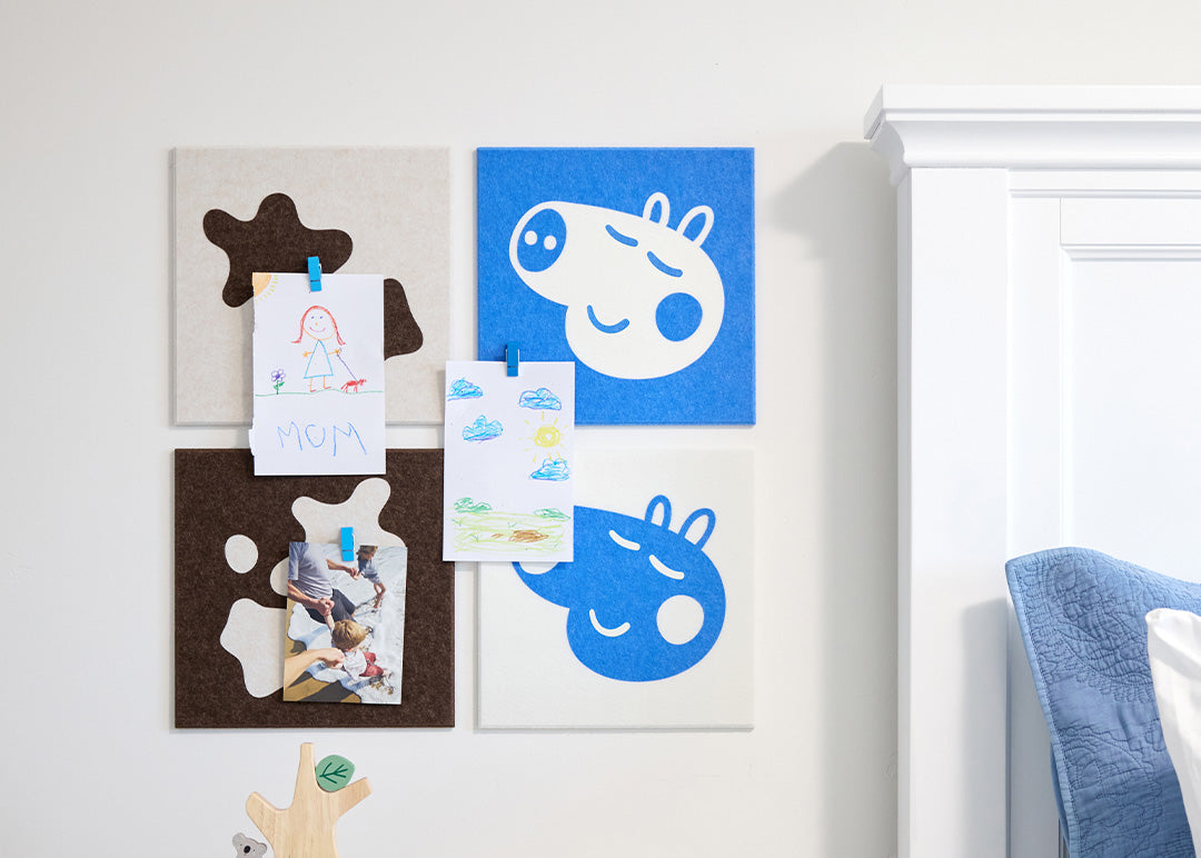 Children's artwork displayed on a decorative wall panel with colorful shapes.