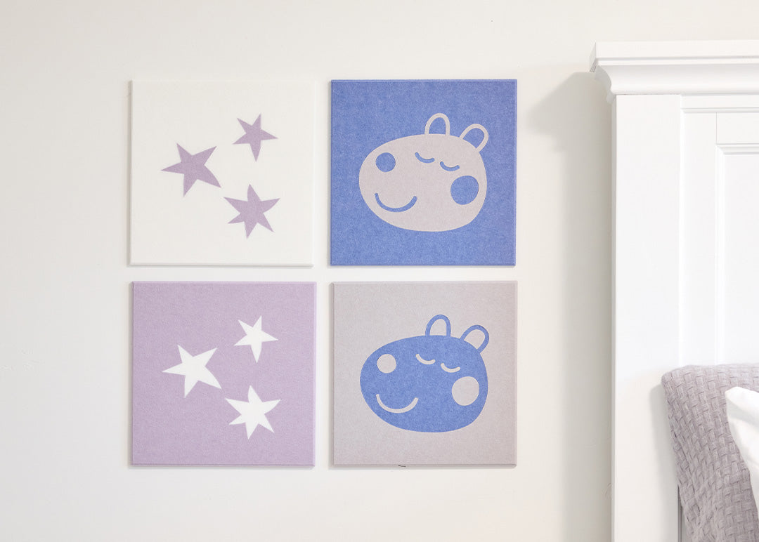 Four square wall art pieces with star and sheep designs on a white wall.