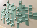 Green textured dimensional tiles arranged on wall in varying 3D heights and orientations.