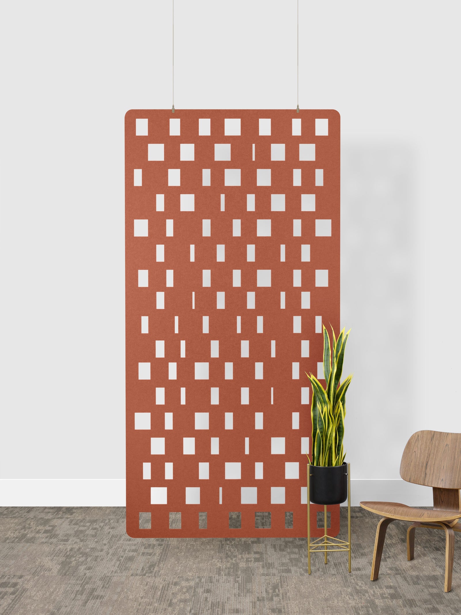 Decorative acoustic felt panel screen with geometric pattern in a room with a chair and plant.