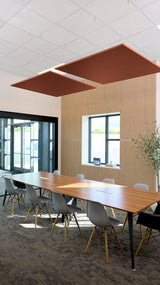 Two rust-brown square acoustic baffles suspended from white drop ceiling above conference table.