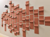 Terracotta-colored three-dimensional tiles arranged in a wave pattern on a beige wall.