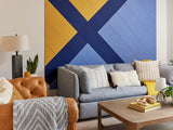 Gray upholstered sofa with striped and solid pillows in living room setting with geometric wall art.