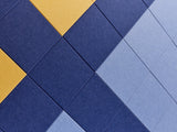 Overlapping diamond-patterned tiles in navy blue, light blue, and yellow arranged in diagonal rows.
