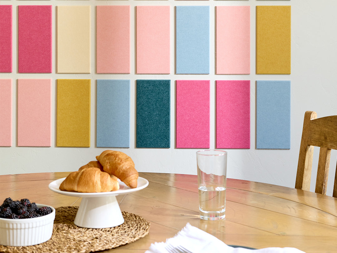 Dining table with pastries, a glass of water, and a bowl of berries against a colorful wall.
