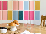Dining table with pastries, a glass of water, and a bowl of berries against a colorful wall.