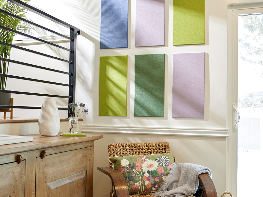 Felt Right wall art in shades of blue, purple, and green felt rectangles on a wall with a sliding door and a chair with a decorative pillow.