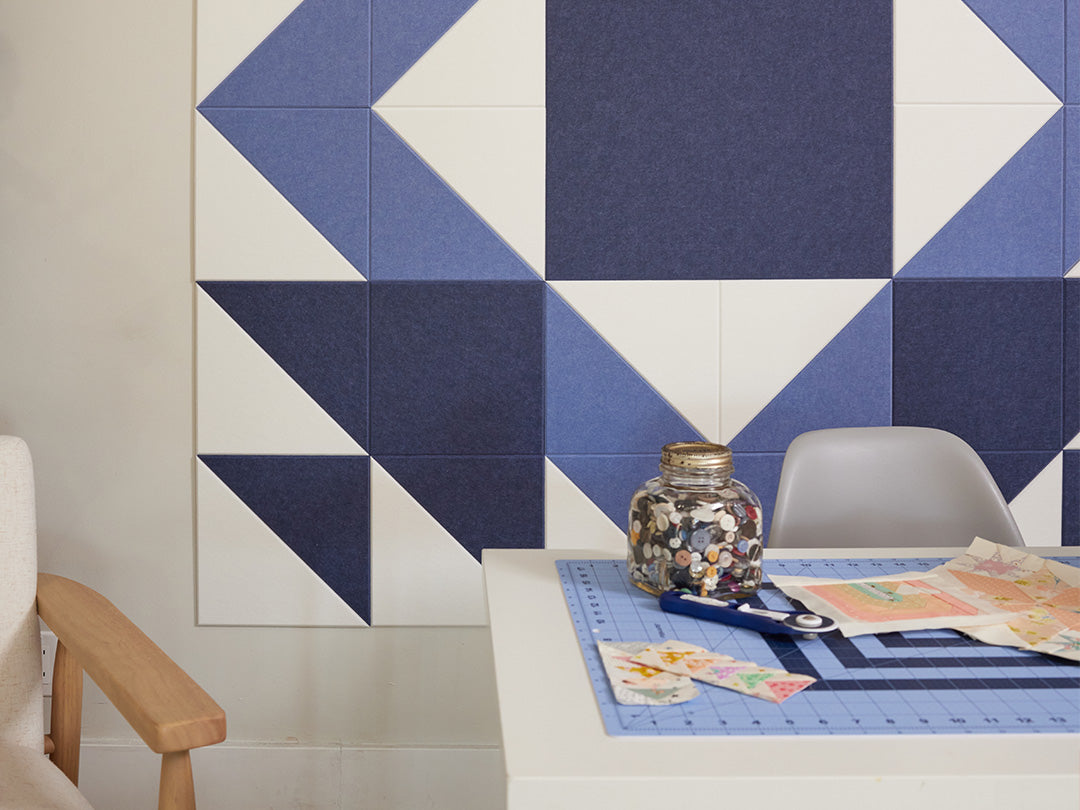 Geometric patterned wall art with blue and white tiles in a room setting.