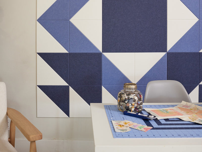 Geometric patterned wall art with blue and white tiles in a room setting.