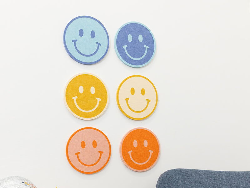 Set of six smiley face coasters in different colors on a white background