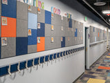 Felt Right wall art design in a hallway of a school that is pinable and using grey, blue, and orange squares.