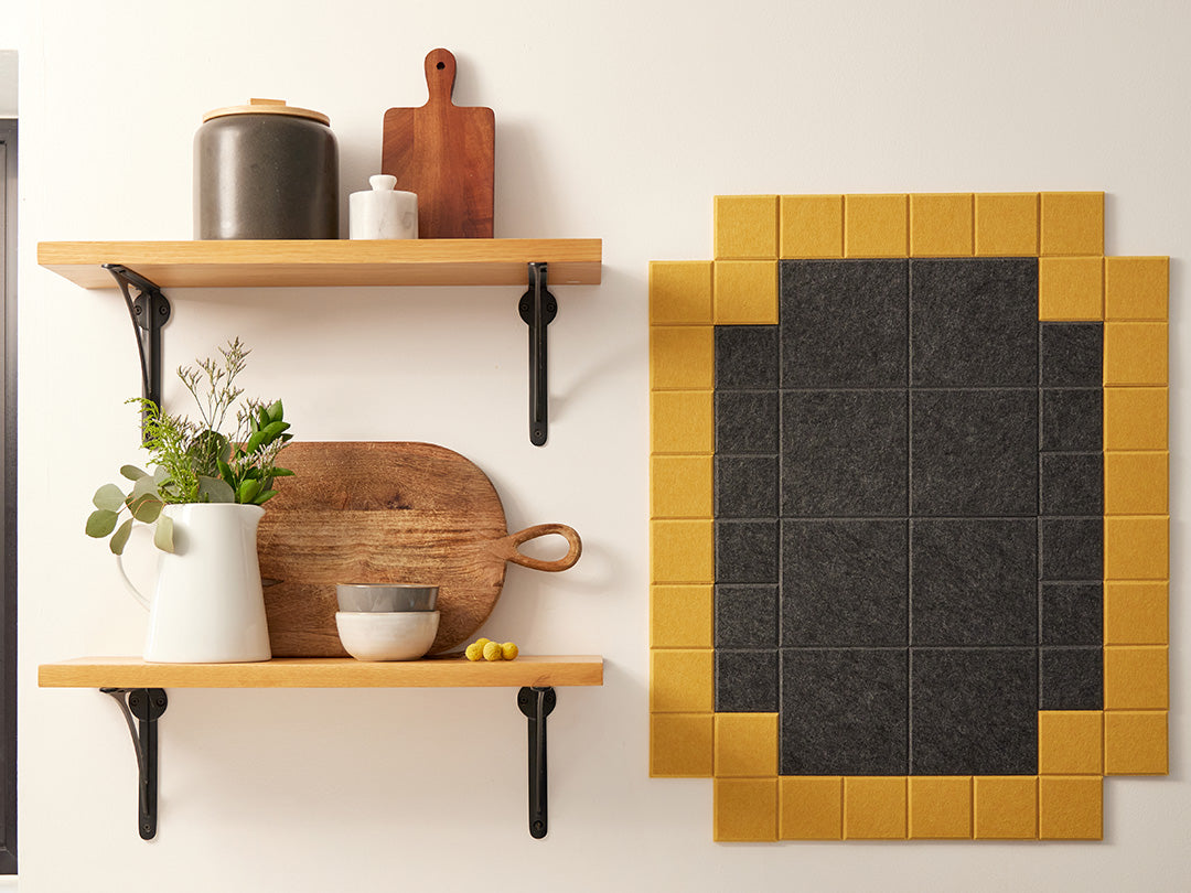 Felt Right wall art tiles in shades of black and yellow creating a framed look on a wall in a kitchen by shelves and home decor