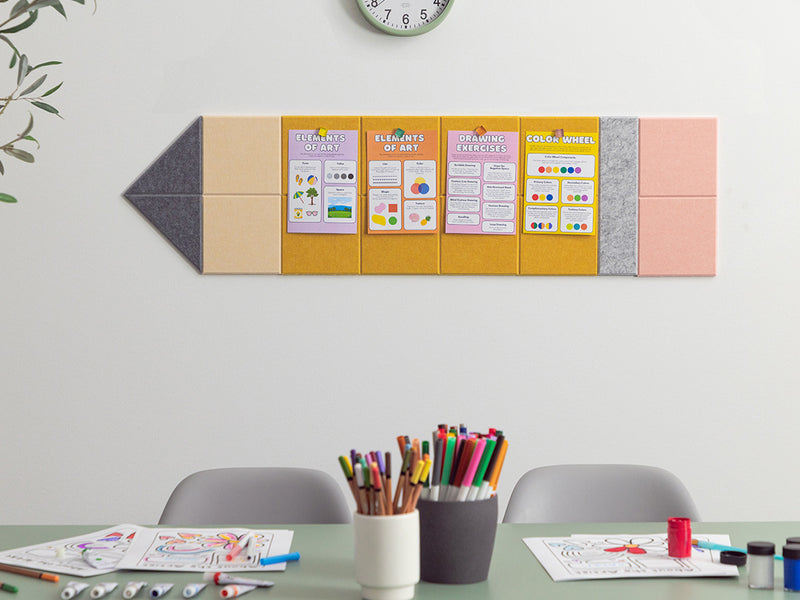 Colorful wall-mounted bulletin board with educational posters above a table with art supplies.