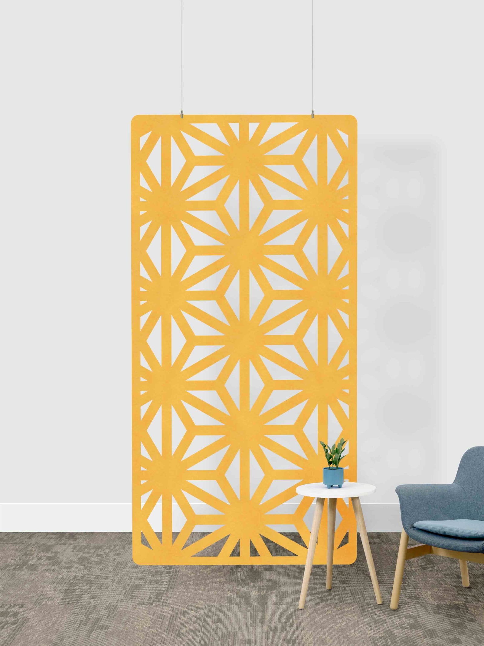 Yellow geometric patterned screen against a white wall with a small table and chair.