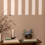 Decorative setup with books, a candle, and a small plant against a striped wall.