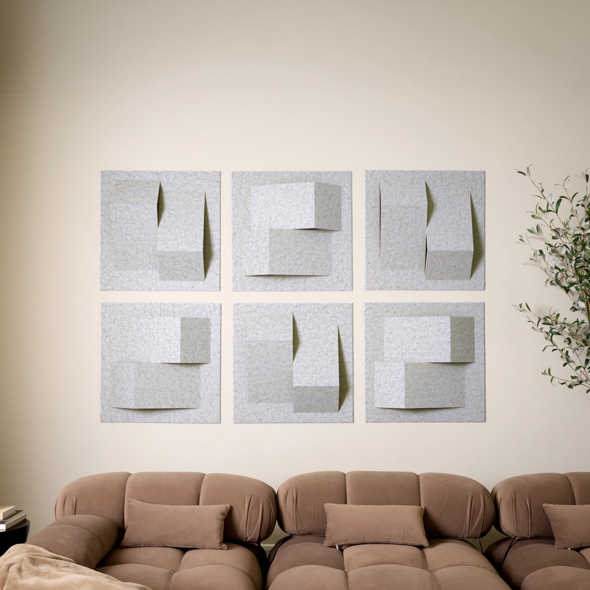 Grey acoustic felt wall tiles arranged in a modern 3D design  above a sofa