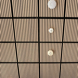 A close-up of a modern ceiling with a grid pattern of light wood slats and black grout lines, featuring three white circular ceiling-mounted sensors or diffusers.