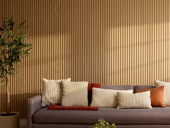 Wood Slats in Oak Latte on a wall behind a grey couch