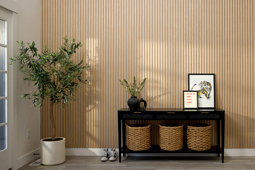 Entryway with decorative items including a plant, baskets, and a small table against a wooden paneled wall.