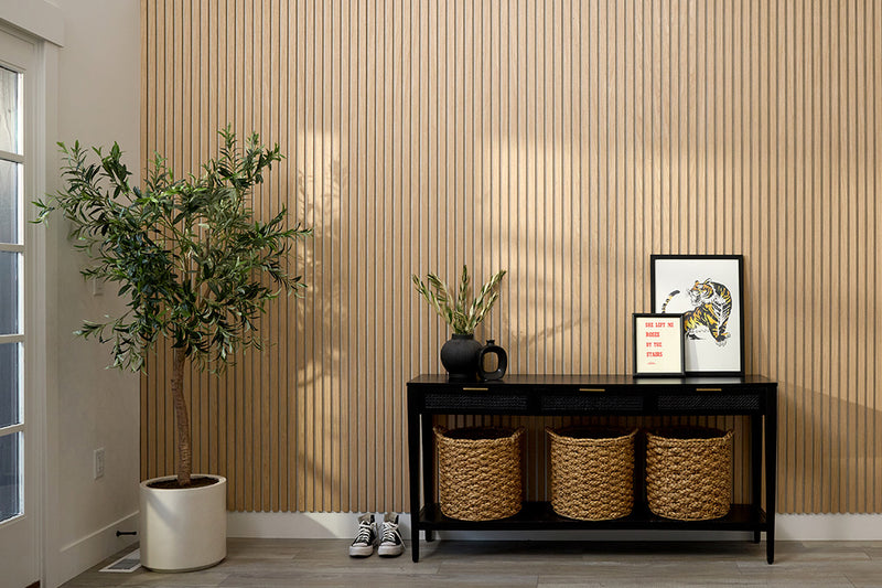 Entryway with decorative items including a plant, baskets, and a small table against a wooden paneled wall.