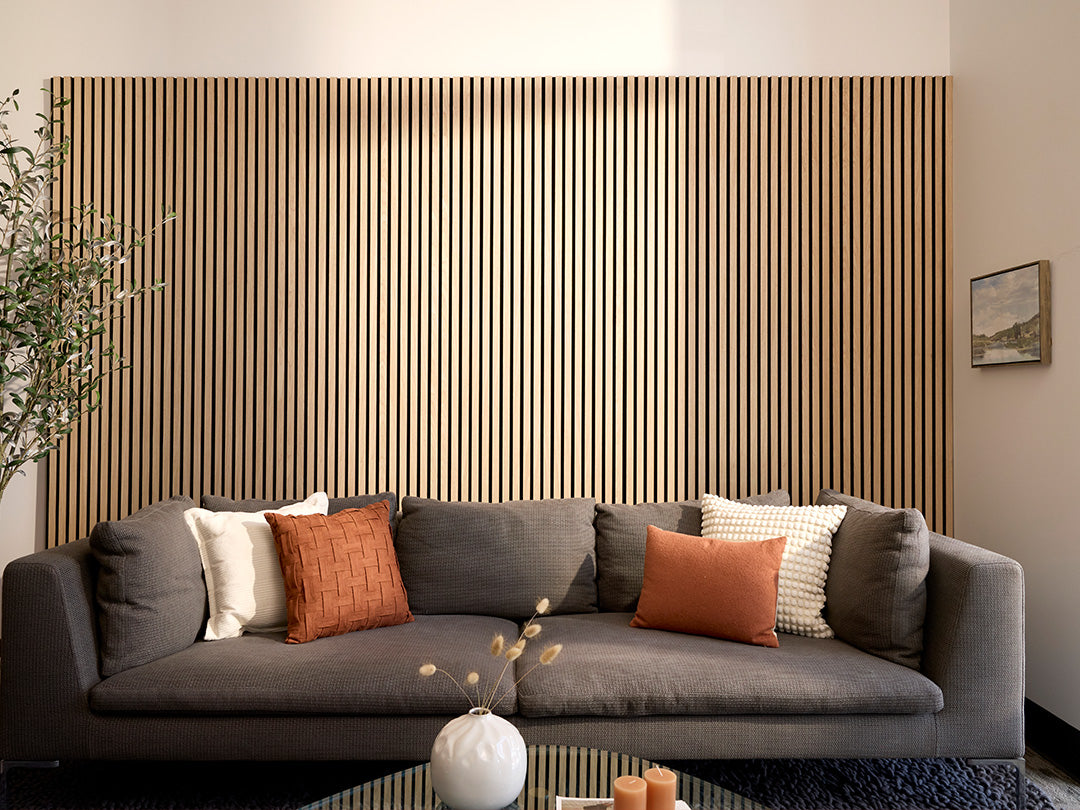 Gray sofa with decorative pillows against a wooden panel wall in a living room setting.