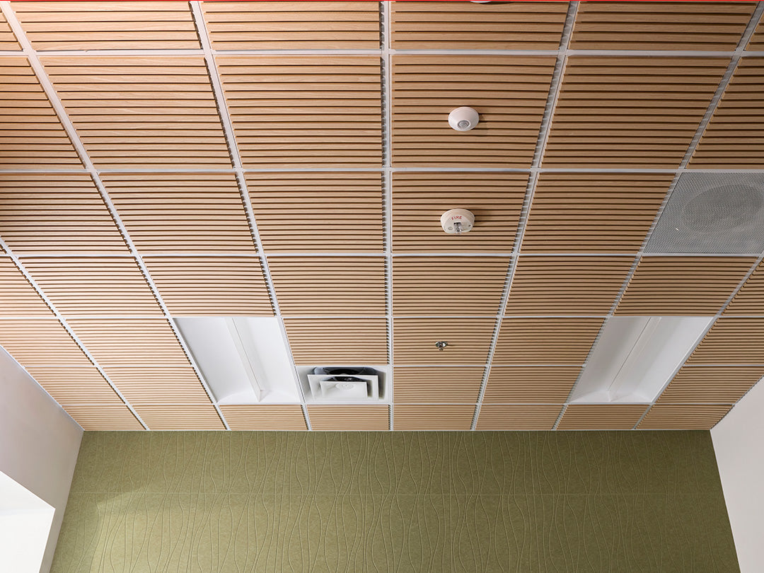 Ceiling with wooden paneling and a fire alarm in an indoor setting
