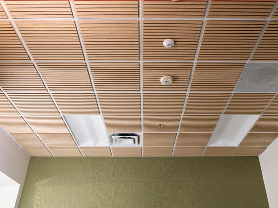 Ceiling with wooden paneling and a fire alarm in an indoor setting