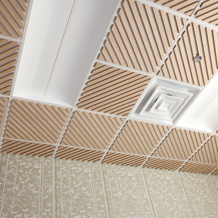 A ceiling grid with square acoustic panels featuring diagonal wood-look slats, white trim, and a central square vent or diffuser, installed above a patterned beige wall.