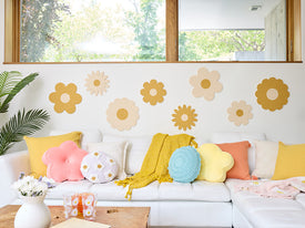 Decorative flower wall art on a white wall with a sofa and colorful pillows.