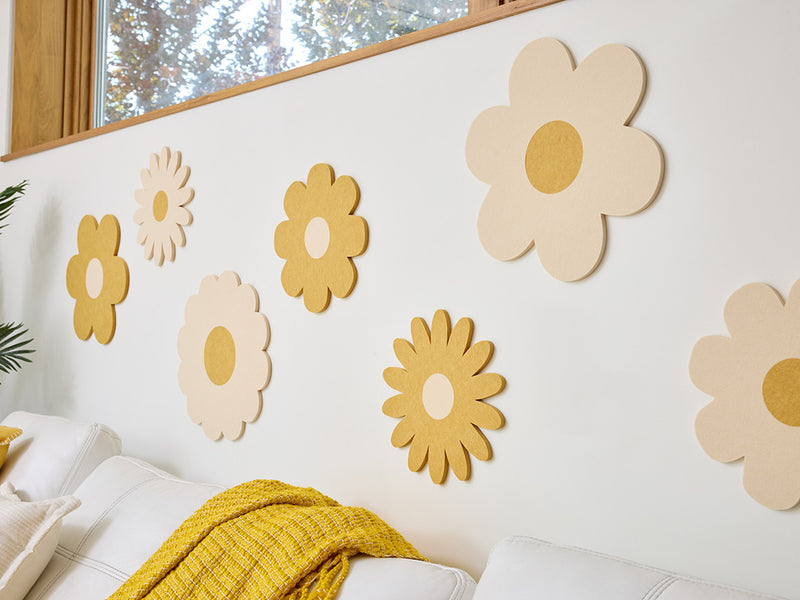 Decorative flower wall art on a white wall with a sofa and colorful pillows.