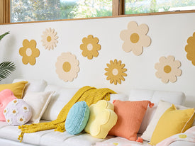 Decorative flower wall art on a white wall with a sofa and colorful pillows.