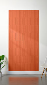 Orange Felt Right 4’ x 8’ PET felt panel with staggered lines engraved into the material against a white wall. A plant and chair are in the foreground.