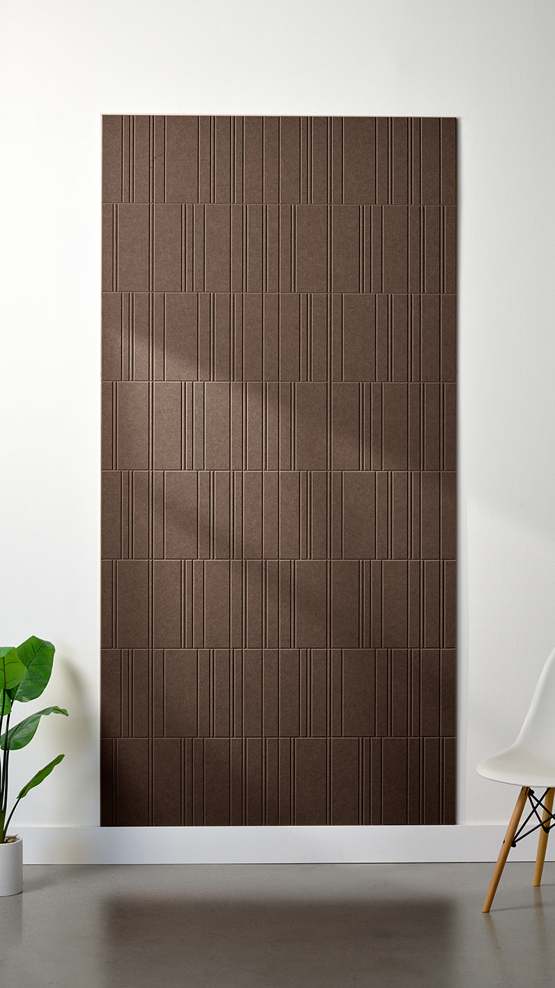 Brown Felt Right 4’ x 8’ PET felt panel with staggered lines engraved into the material against a white wall. A plant and chair are in the foreground.