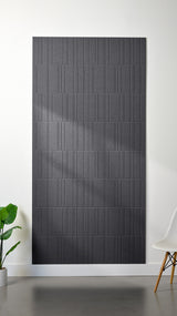 Grey Felt Right 4’ x 8’ PET felt panel with staggered lines engraved into the material against a white wall. A plant and chair are in the foreground.