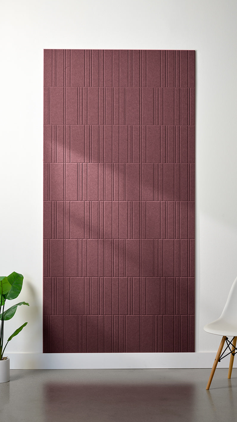 Maroon Felt Right 4’ x 8’ PET felt panel with staggered lines engraved into the material against a white wall. A plant and chair are in the foreground.