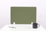 Sage green desk divider with curved line pattern, white feet, displayed on white desk with mug and pens.