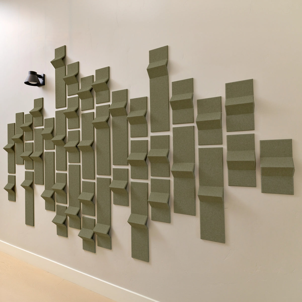 Green felt acoustic tiles on a wall with points of dimension